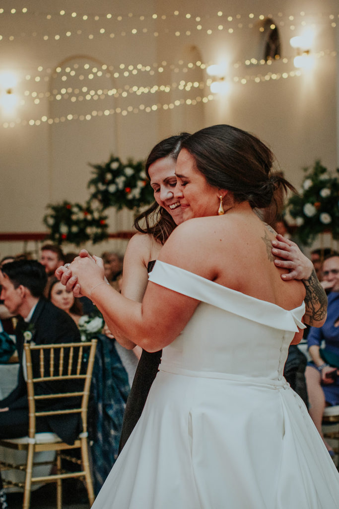 the bride and her sister share a special dance as they honor their father's memory