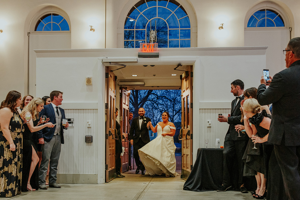 a couple joyfully enters their DC wedding reception, surrounded by family and friends