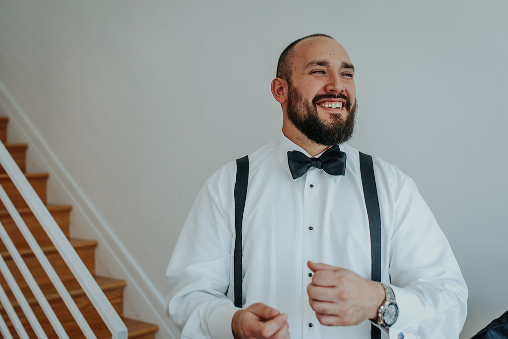 Groom smiles and laughs with groomsmen during getting ready