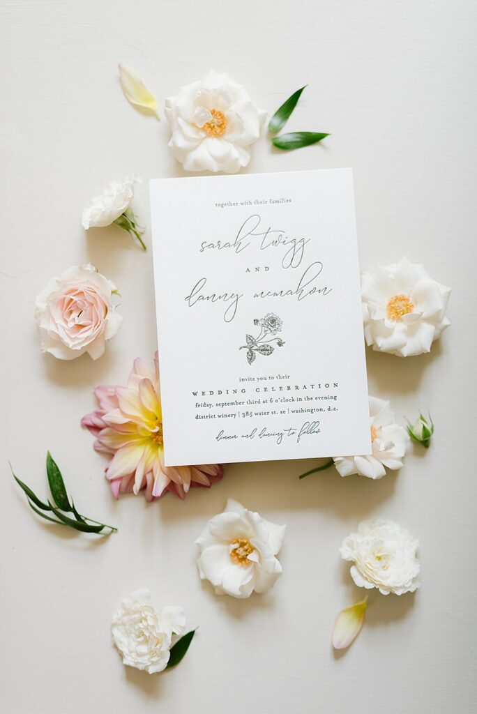 Flat lay of a couple's letterpress invitation, with dahlia floral motif